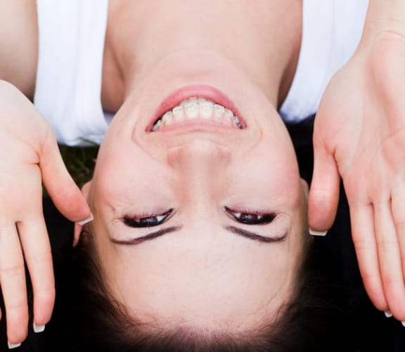 Woman laying on the grass with her hands next to her face