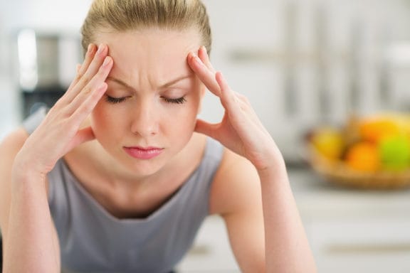 Woman holding her hand on her forehead and looking down in pain